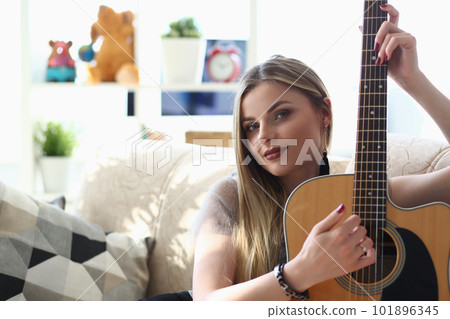 Talented purposeful young woman holds guitar in hands Talented purposeful young woman holds guitar in hands 101896345