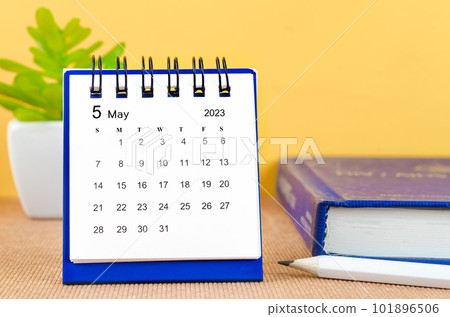 The May 2023 Monthly desk calendar for 2023 with a book on yellow background. 101896506