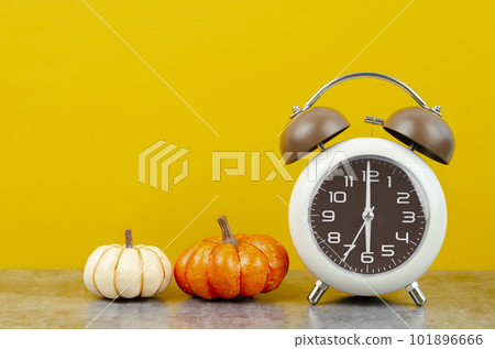 The Vintage alarm clock with autumn pumpkins on yellow background. 101896666