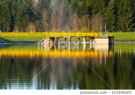 Landscape with a yellow metallic bridge construction and concrete spillway 101896805