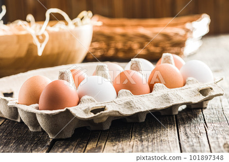 Whole chicken eggs in eggbox on wooden table. Whole chicken eggs in eggbox on wooden table. 101897348