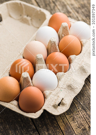 Whole chicken eggs in eggbox on wooden table. Whole chicken eggs in eggbox on wooden table. 101897349