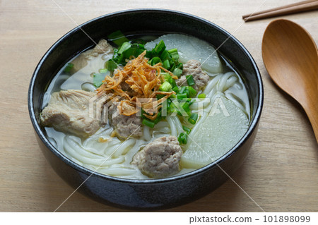 close up view of vietnamese rice noodles soup with pork in a ceramic bowl on wooden table. asian homemade style food concept. close up view of vietnamese rice noodles soup with pork in a ceramic bowl on wooden table. asian homemade style food concept. 101898099