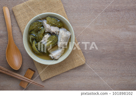 top view of bitter gourd clear soup with pork rib in a ceramic bowl on wooden table. asian homemade style food concept. 101898102