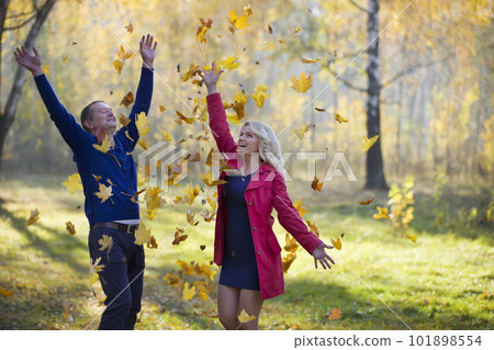 Loving couple in the autumn park. Spouses of middle age for a walk.Men and women throw yellow leaves 101898554