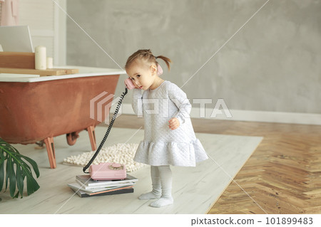 A sweet, pleasant little girl is talking on the phone with a telecom operator. 101899483