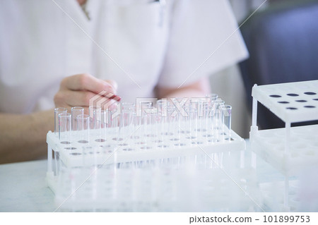 Hands of the doctor and glass test tubes. Medical containers for analysis on the background of hands Hands of the doctor and glass test tubes. Medical containers for analysis on the background of hands 101899753