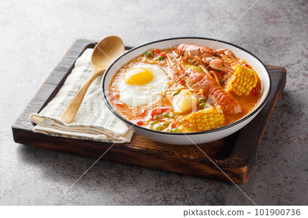 Chupe de Camarones Peruvian Crawfish Chowder with tomatoes, corn, pepper, potato, green peas and egg close-up on a bowl. Horizontal Chupe de Camarones Peruvian Crawfish Chowder with tomatoes, corn, pepper, potato, green peas and egg close-up on a bowl. Horizontal 101900736
