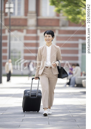 一位 50 歲出頭的女商人提著購物袋行走。 101900842