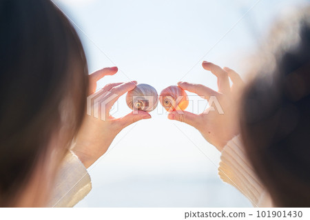 A young woman's hand holds up a shell picked up on the beach A young woman's hand holds up a shell picked up on the beach 101901430