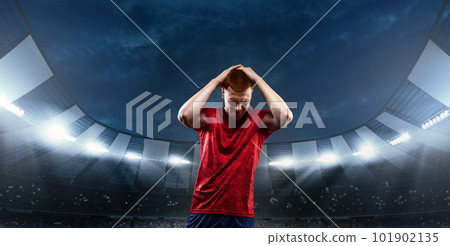 Loosing game. Young man, professional sportsman in red uniform holding head with hands in despair and sadness at 3D stadium with flashlights Loosing game. Young man, professional sportsman in red uniform holding head with hands in despair and sadness at 3D stadium with flashlights 101902135
