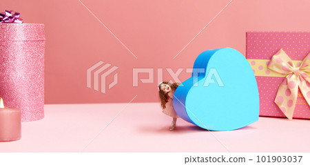 Little happy girl, child carrying giant, blue, heart shaped present box against pink background. Happy holidays, gifts Little happy girl, child carrying giant, blue, heart shaped present box against pink background. Happy holidays, gifts 101903037