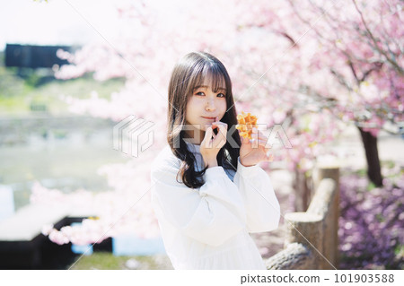 Girl eating waffles in front of cherry blossoms 101903588