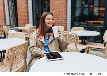 Young woman enjoying a coffee, sitting on the cafe terrace on the modern city street. Person sitting at table and using tablet outdoors. Traveler, Online education, working or shopping concept Young woman enjoying a coffee, sitting on the cafe terrace on the modern city street. Person sitting at table and using tablet outdoors. Traveler, Online education, working or shopping concept 101903939