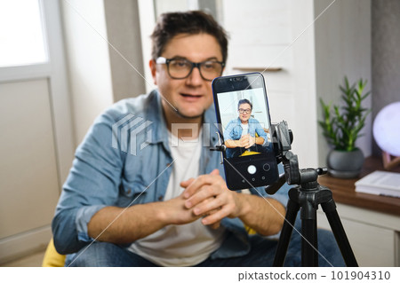 Video blogger recording content to channel at home before smartphone fixed on tripod Video blogger recording content to channel at home before smartphone fixed on tripod 101904310