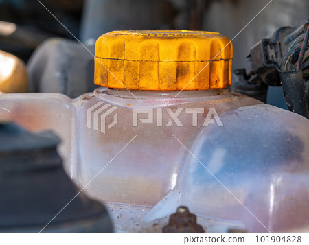 Plastic tank with a yellow cap for antifreeze of the car engine cooling system. 101904828