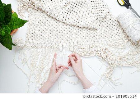 Creative hobby handmade macrame for home decoration. Girl weaves macrame. Woman weaving macrame panels for home decor. Flat lay, top view Creative hobby handmade macrame for home decoration. Girl weaves macrame. Woman weaving macrame panels for home decor. Flat lay, top view 101905514