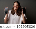 Closeup of funny smiling teen girl showing blank screens of two smart phones holding in hands 101905820