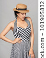 Pensive mixed race woman in chequered summer dress and canotier straw hat 101905832