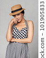 Mixed race woman in chequered summer dress and canotier straw hat 101905833