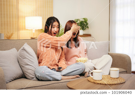 Young woman lesbian couple in sweater sits on comfortable sofa t Young woman lesbian couple in sweater sits on comfortable sofa t 101906040