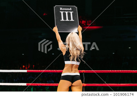 blonde ring girl demonstrate sign with number third round during fight MMA on dark background blonde ring girl demonstrate sign with number third round during fight MMA on dark background 101906174