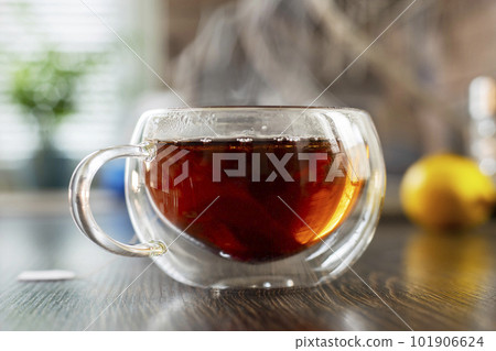 A hot cup of freshly brewed black tea with steam on wooden table 101906624