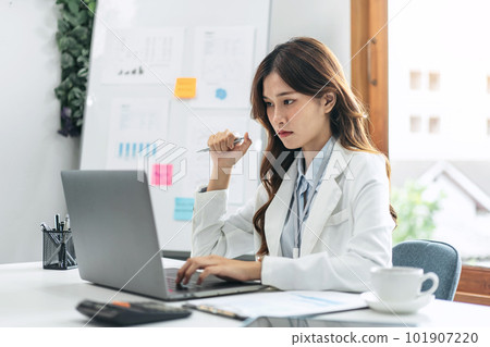 Businesswoman is reading marketing plan report on laptop to anal Businesswoman is reading marketing plan report on laptop to anal 101907220