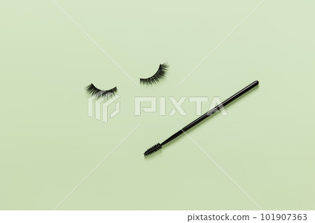Creative layout with eyelashes and brush mascara. Closed eyes on green background Creative layout with eyelashes and brush mascara. Closed eyes on green background 101907363