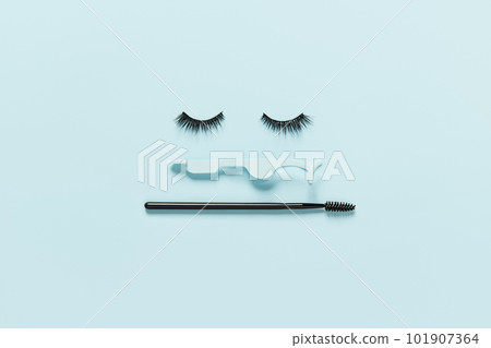 Creative layout with eyelashes, applicator and mascara brush. Closed eyes on pastel blue background Creative layout with eyelashes, applicator and mascara brush. Closed eyes on pastel blue background 101907364