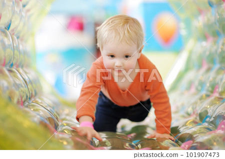 Active toddler boy having fun on inflatable attraction in entertaining center. Funny child is playing on indoor playground. Kids amusement park. 101907473