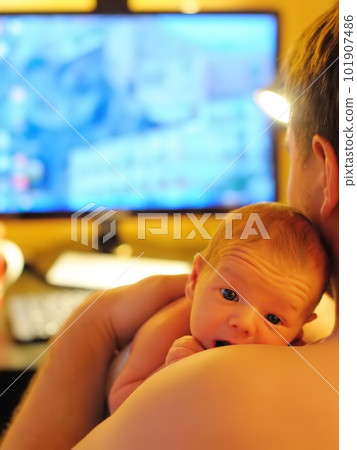 Mature father holding his sweet newborn baby while working on computer at home. Home office and parenthood at same time. Parenting. 101907486