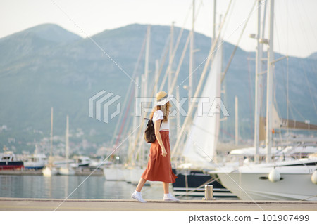 Charming young tourist woman travel by Mediterranean coast. Attractive red-haired girl on the background of sea and yachts. Yacht rental. Tourism and travel 101907499