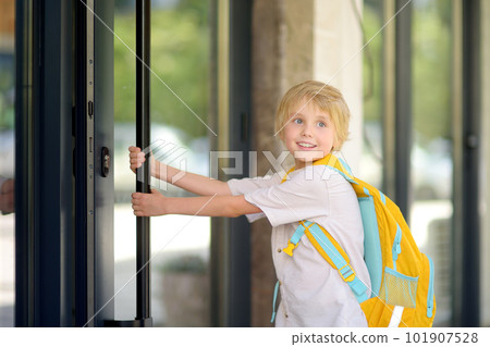 Little schoolboy leaves the house to go to school after holiday. Child in a yard of schoolhouse. Quality education for children. Kids back to school 101907528