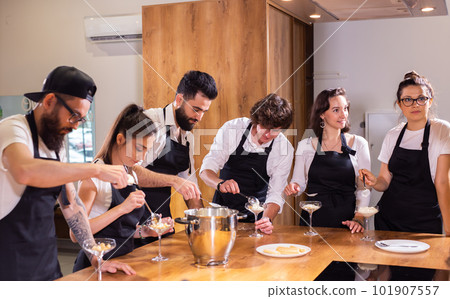 Chef teaching trainees how to make ice cream. Cooking tasty ice cream dessert made from chocolate and vanilla in glass bowl Chef teaching trainees how to make ice cream. Cooking tasty ice cream dessert made from chocolate and vanilla in glass bowl 101907557