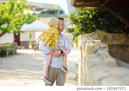 Preschooler boy with his dad are visiting outdoors petting zoo. Child having fun in farm with animals. Children and animals. Entertainment for family with kids on holidays 101907571