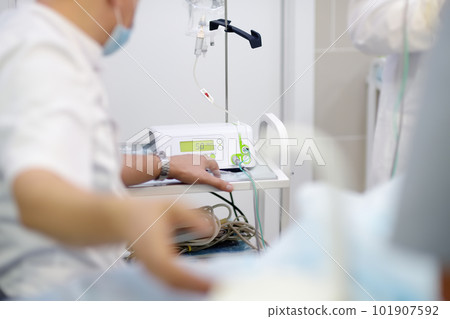 Anesthetist giving anesthesia to patient before operation in a clinic. Anesthesiologist observing the monitor readings while the patient is being anesthetized while surgery operation 101907592