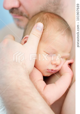Mature father holding his sweet newborn baby. The baby sleeping in the arms of the father. 101907689