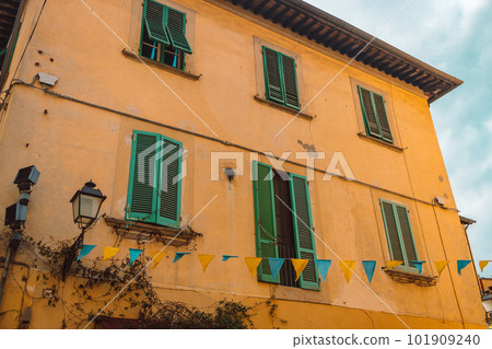 Windows on yellow painted facade of the house. Window with green shutters on a yellow house. Colorful architecture in Pisa, Italy. 101909240
