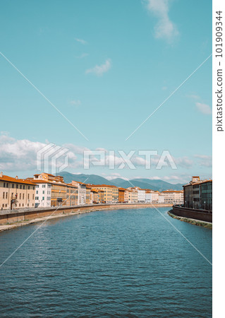 A beautiful view of buildings along the Arno river in Pisa, Italy. A bridge passes over the river and houses on both sides are overlooking the water 101909344