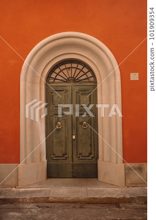 Vintage brown green wooden door with orange wall in Italy Vintage brown green wooden door with orange wall in Italy 101909354