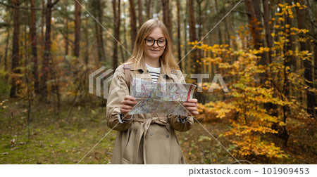Travelers explore the mountainous forest map. Happy woman hiking and looking at map outdoors in nature. 101909453