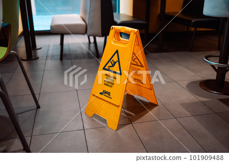 Yellow Caution slippery wet floor sign on the wet ground Yellow Caution slippery wet floor sign on the wet ground 101909488
