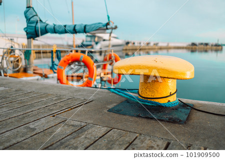 Rope mooring and bollard against the background of sea water and yachts 101909500
