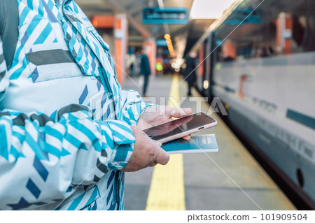 60s woman in face mask waiting on a train station platform with passport and tickets 60s woman in face mask waiting on a train station platform with passport and tickets 101909504