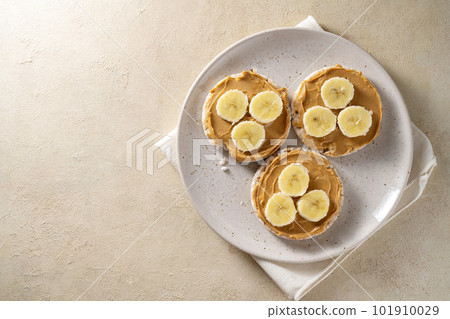 Rice cakes with banana and peanut butter, healthy protein snack, top view, copy space Rice cakes with banana and peanut butter, healthy protein snack, top view, copy space 101910029