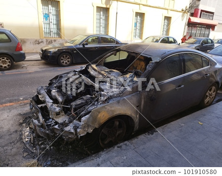 A car with a burned hood is parked on a street in the city 101910580