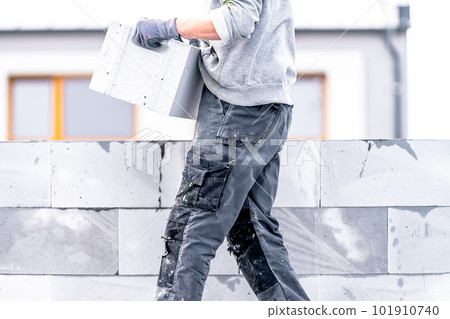 a mason builds the wall of a house from concrete bricks a mason builds the wall of a house from concrete bricks 101910740