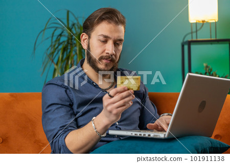 Young lebanese man using credit bank card and laptop, transferring money, purchases online shopping 101911138