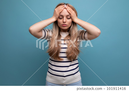 close-up of a sad girl in casual clothes holding her head on a blue isolated background 101911416